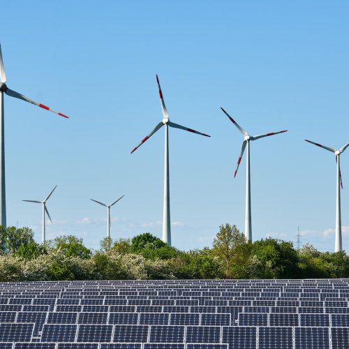 Solarpark mit Windrädern im Hintergrund